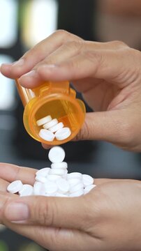 close up woman hand holding a medicine, with pours the pills out of the yellow orange medicine bottle. Stop drug use Taking Medication Caring for the health care medical concept.