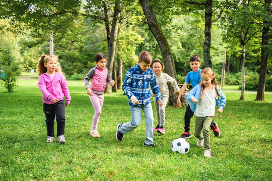 Group of young childs playing soccer ball outdoors in park