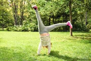 Obraz premium 9 year old girl tries gymnastics spontaneously during a walk in the park.