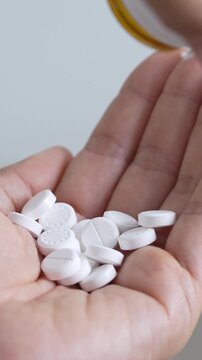 close up woman hand holding a medicine, with pours the pills out of medicine bottle. Stop drug use Taking Medication Caring for the health care medical concept.
