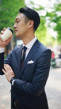 Businessman drinking takeaway coffee on a brick paved street in Tokyo