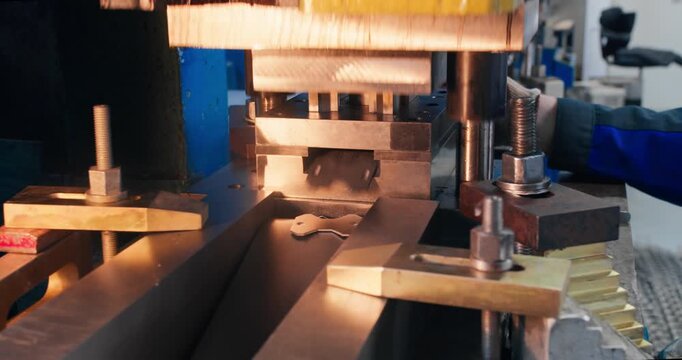 Metal stamping press in operation during factory production. Close-up of mechanical blanking equipment manufacturing metal parts