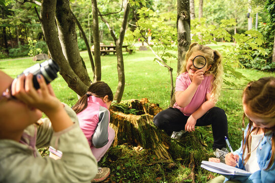 Group of happy school kids learning about environment and insects during field trip