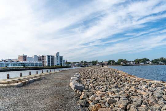 Salem waterfront skyline with rocky jetty and calm harbor, modern buildings under blue sky panorama.