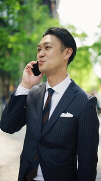 Japanese businessman laughing during a phone call on a city street