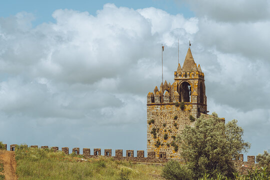 The historic medieval Castle of Montemor-o-Novo in Portugal under a dramatic cloudy sky.