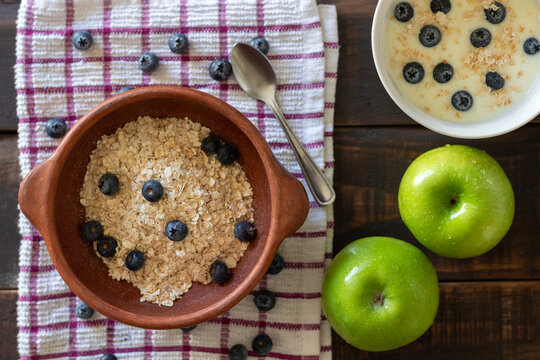 Aerial view of a healthy breakfast or snack consisting of green apples, a small bowl of yogurt, and a small bowl of oatmeal with blueberries