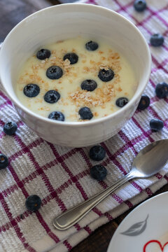 A delicious, healthy breakfast in a bowl with yogurt, oatmeal, and blueberries on a kitchen tablecloth
