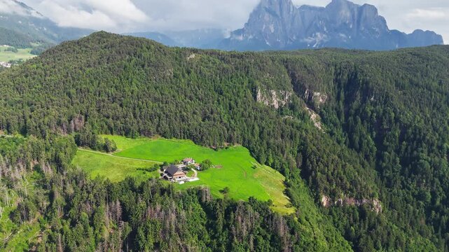 Farmhouses among green meadows and forest in South Tyrol, Italy. Aerial footage of Alpine countryside with rural character for holidays in nature and escapes from city life