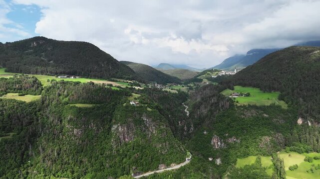 Drone footage of Dolomite Alps in South Tyrol, Italy. Broad mountain landscape with forested valleys and green meadows