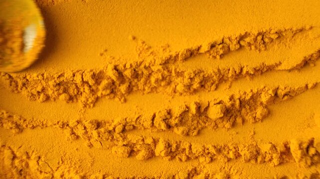 Close-up of turmeric powder being stirred with a spoon top view
