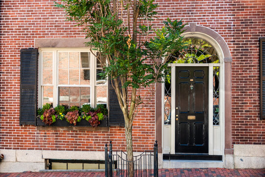 Brick townhouse facade with tree and iron door in Boston