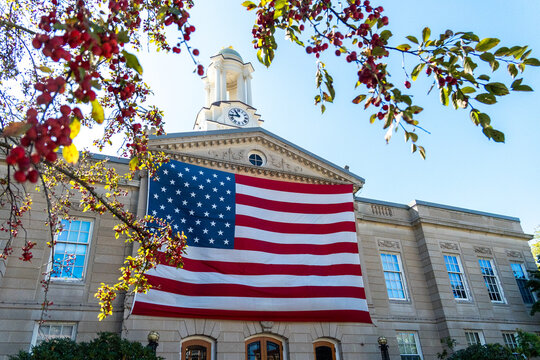 Civic building with American flag draped across facade under blue sky