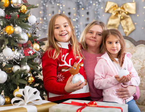 Merry Christmas! Happy mother with two girls near the Christmas tree in the living room. Christmas Eve, in anticipation of holiday