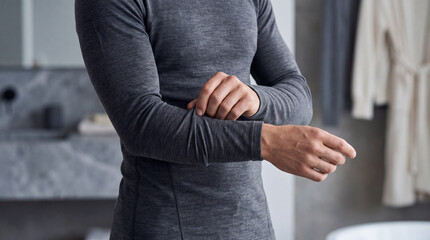 Fototapeta premium Man adjusting a fitted thermal base layer indoors, showing warm functional clothing for cold weather, winter comfort, outdoor activity and seasonal wardrobe