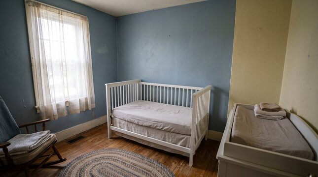 Empty white crib in a quiet nursery room with soft window light