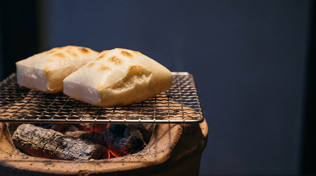 Rice cakes puffing up on a grill over glowing charcoal at night