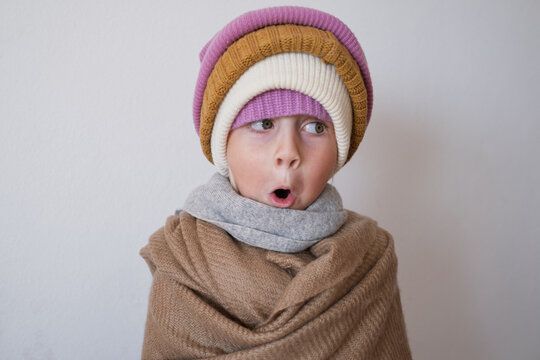  surprised little girl wearing multiple warm winter knitted beanies