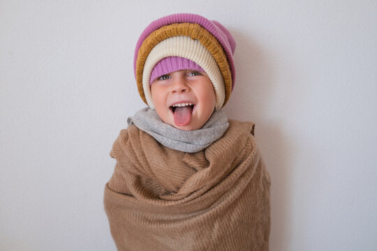  surprised little girl wearing multiple warm winter knitted beanies