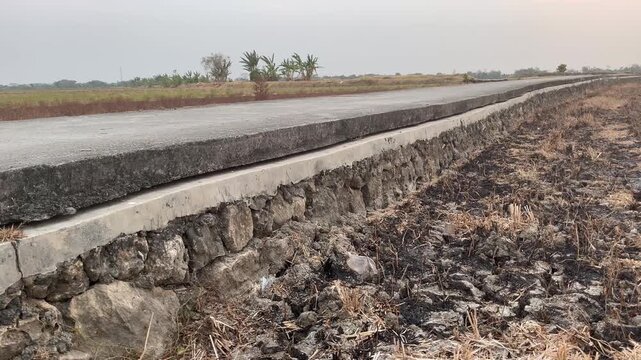 Rural concrete road construction with stone retaining wall