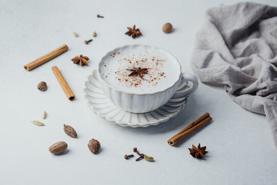 Chai latte with milk foam, cinnamon and star anise on a light background