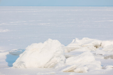 Expansive frozen winter landscape featuring textured ice chunks and a vast white plain under clear blue sky © reddish