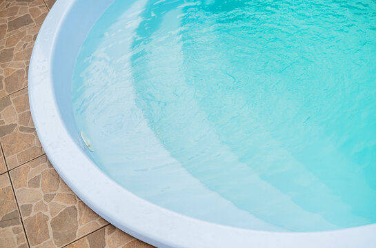 Clear blue water in a round pool next to a tiled background