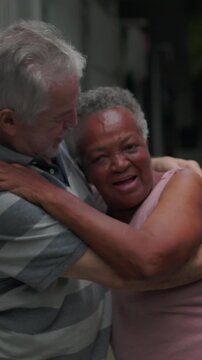 African American senior woman giggling in cheerful embrace with older male partner outdoors sharing heartfelt intimacy and joyful romance in daylight