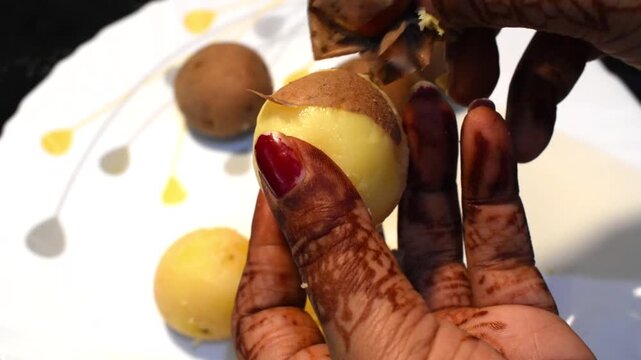 Indian woman&rsquo;s hand peeling a boiled potato or aloo in a home kitchen