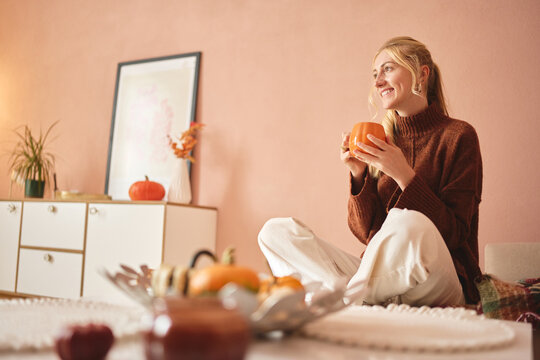 Woman relaxing with a warm drink in autumn home.