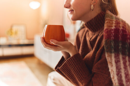 Woman holding a warm mug at home.