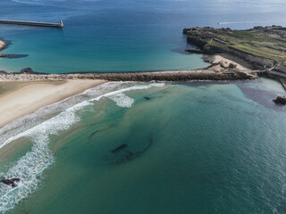 Aerial view of turquoise ocean waves rolling onto a sandy beach with stone breakwaters and coastal cliffs in Tarifa, Spain © Felix Morion