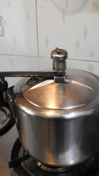 Vertical shot of Pressure cooker on a gas stove releasing steam.