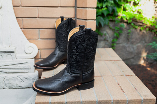 New black men leather boots resting on bricks