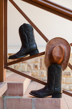 Leather roper boots and a hat on brick steps
