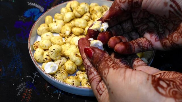 showing crunchiness of roasted makhana by breaking it with hand