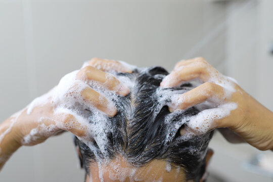 Woman is washing her hair with shampoo.	