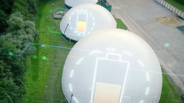 Animated battery graphics appear over biogas storage domes in a cinematic drone view, connecting renewable gas and energy storage for sustainability marketing.