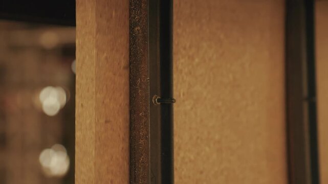 Close up of thick wood particle board chipboard panel sliding through industrial cutting or edging machine with sawdust