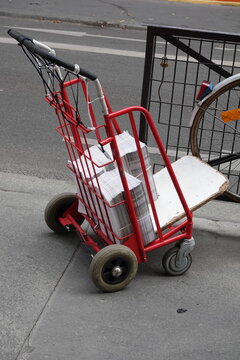 Diable de transport rouge dans la rue pour la distribution de prospectus et journaux
