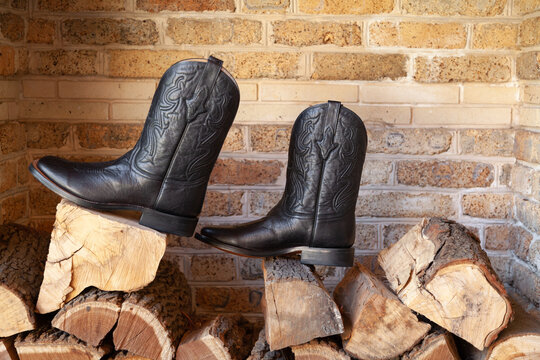Men cowboy boots standing on pile of firewood