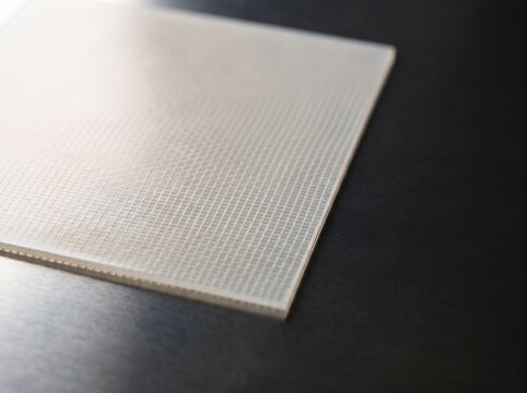 Macro studio photograph of reinforced fluoropolymer cation exchange membrane sheet showing interwoven ptfe micro fiber mesh matrix for mercury free industrial chlor alkali electrolysis cell