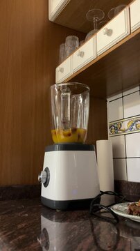 Manos a&ntilde;adiendo fresas a batidora con zumo en vertical