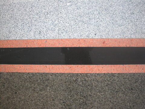 High angle view of polished stone flooring pattern with horizontal black and pink granite borders.