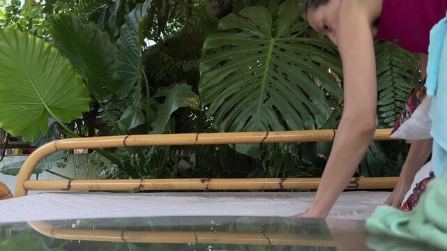 Mujer organizando cama balinesa en el jard&iacute;n