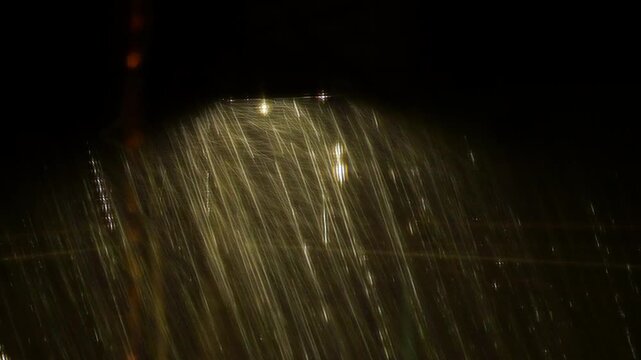 Streaks of Rain Falling at Night Illuminated by Warm Streetlight Glow