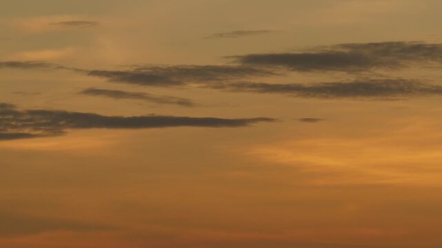 Silhouetted Clouds Against Bold Orange Sunset Gradient Sky