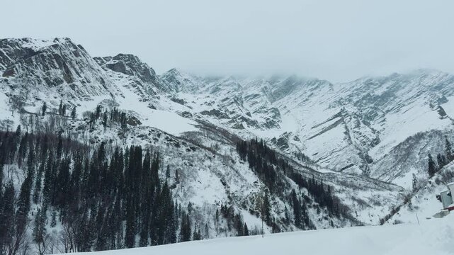 4K shot of snowy Himalayan mountain peaks covered by clouds during the winter season as seen near Atal Tunnel in Manali, Himachal Pradesh, India. Scenic natural background with copy space.