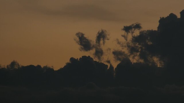 Silhouetted Clouds Against Bold Orange Sunset Gradient Sky