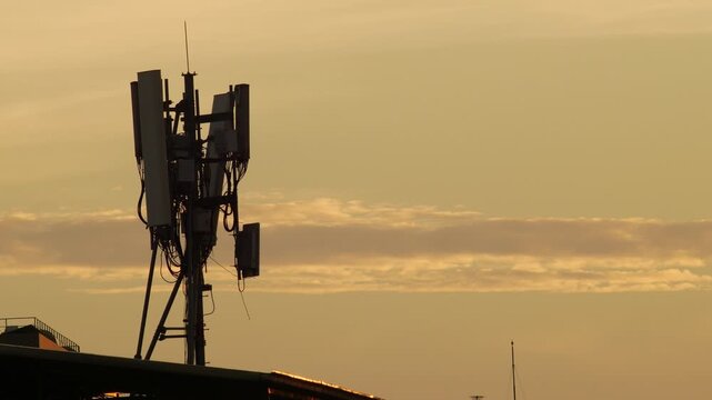 Silhouette of Cell Tower Antenna Array Against Dramatic Orange Sunset